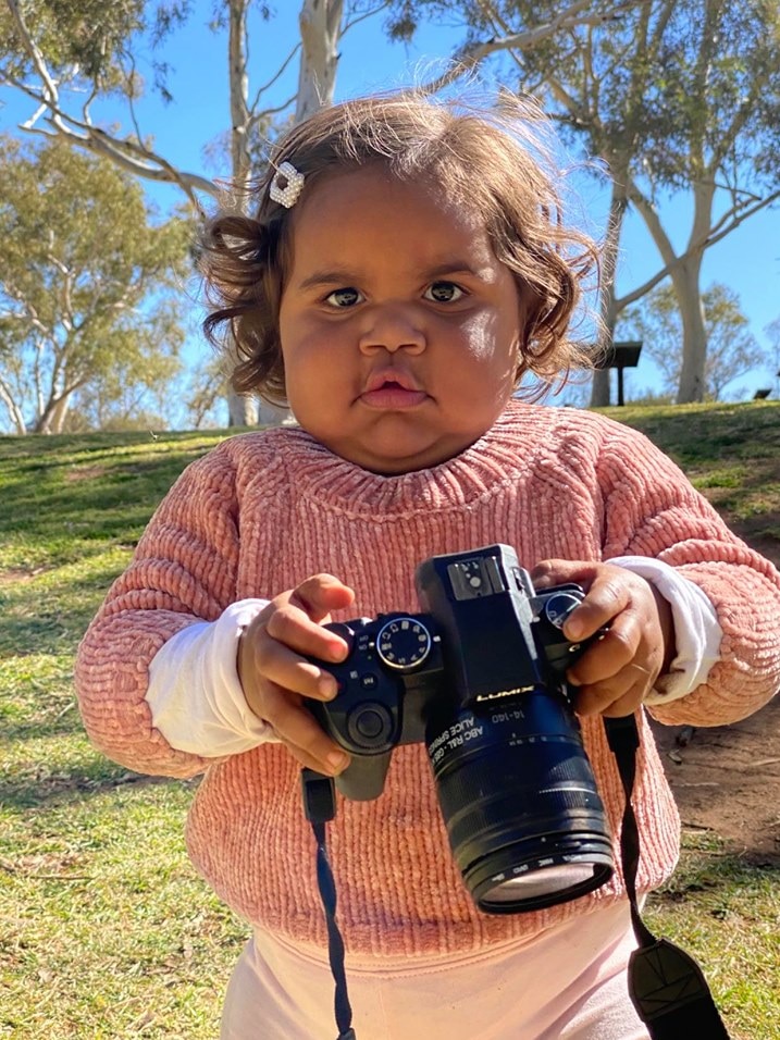 An Aboriginal baby girl holding a camera.