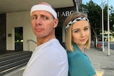 ABC reporters Tom Forbes and Ashleigh Stevenson standing back to back outside the ABC Brisbane building.