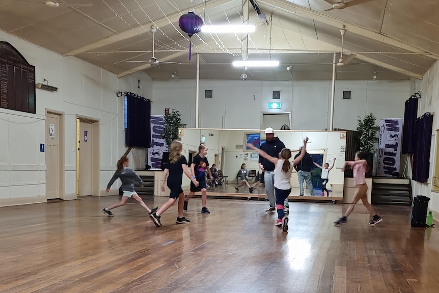 Five students surround their teacher in a dance studio.