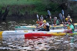 A group of kayakers close together on the Avon River during the Avon Descent.