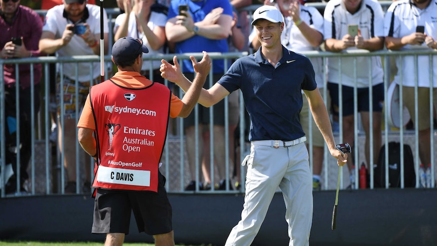 A golfer clasps hands with his caddy.