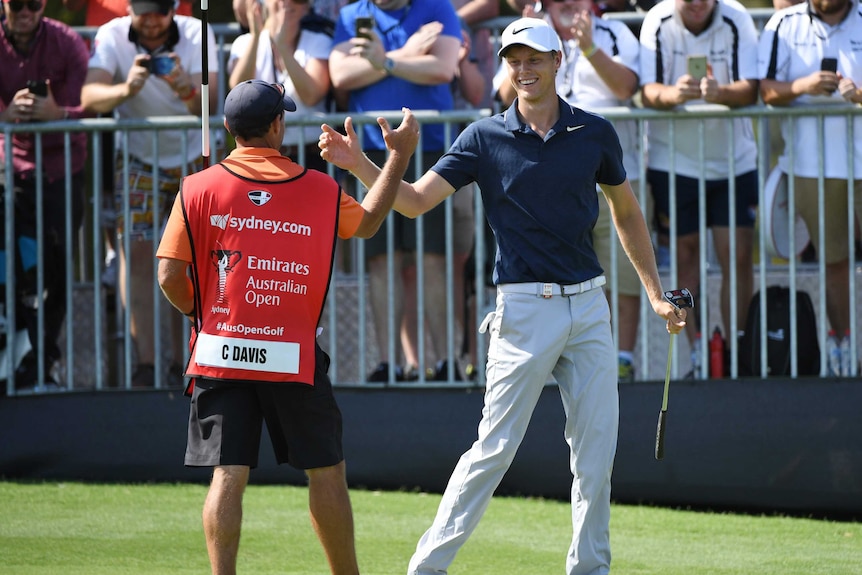 A golfer clasps hands with his caddy.