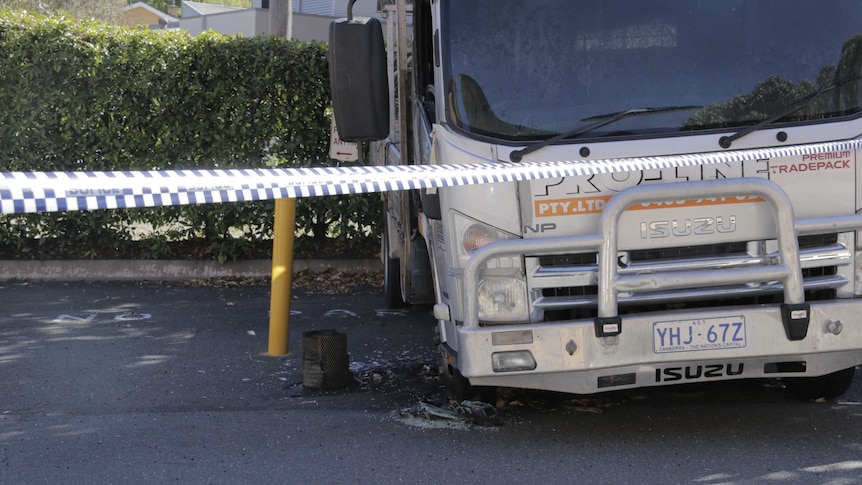 A truck with a broken window and damaged tyre.