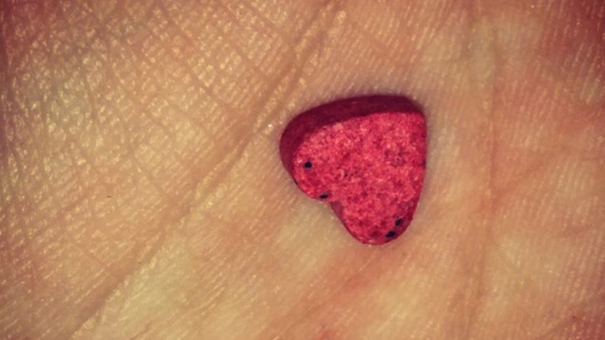 A small heart shaped pill is nestled in someone's hand