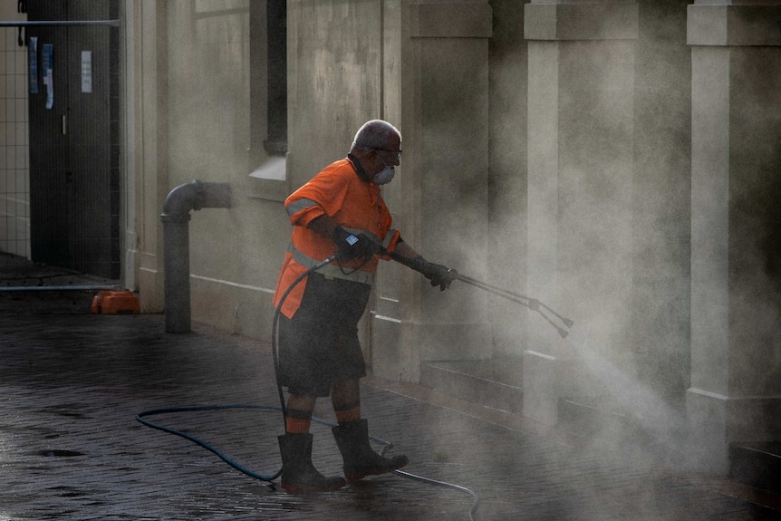 A cleaner in a face mask sanitises Sydney's streets.