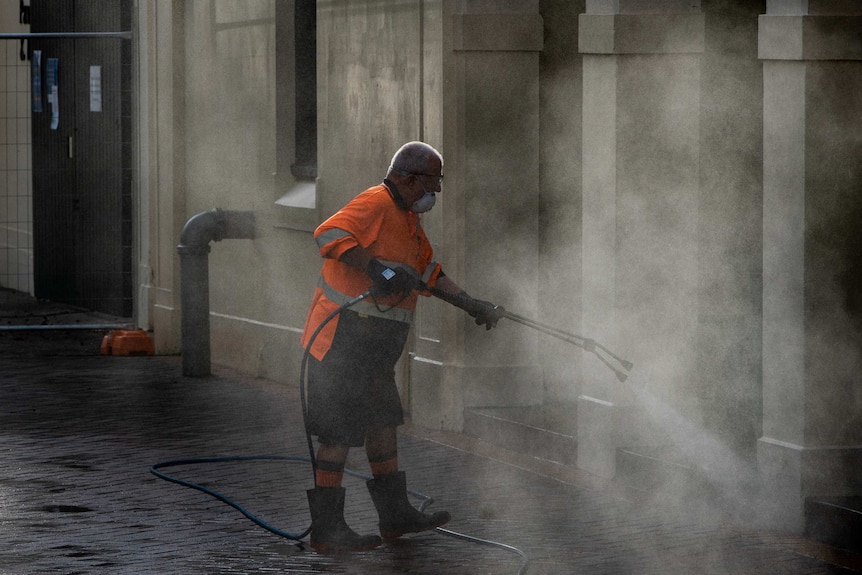 A man in the Sydney CBD spraying down an area