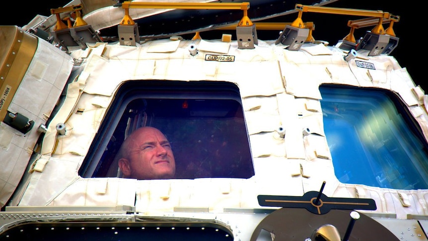 Astronaut Scott Kelly peers out at space.