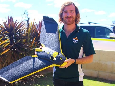 A man stands holding a drone.