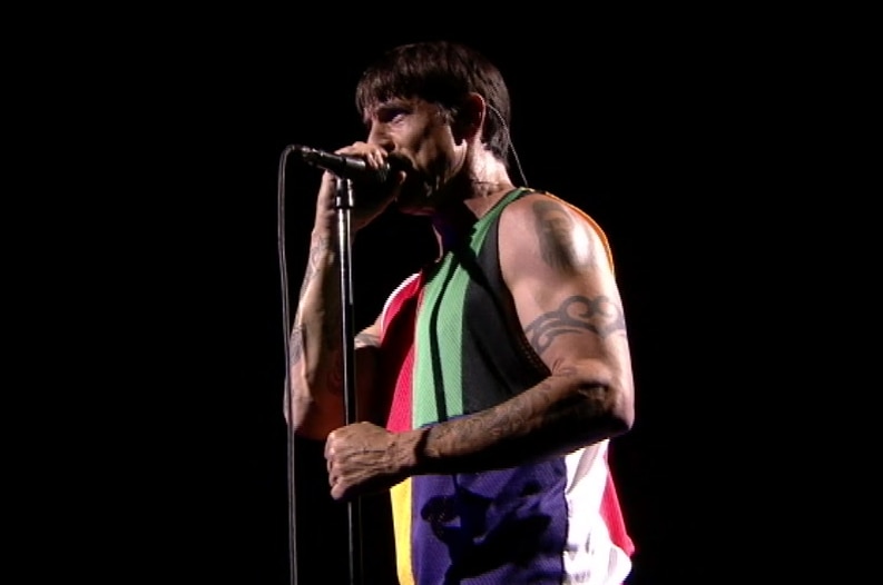 Red Hot Chili Peppers frontman Anthony Kiedis in front of a microphone.