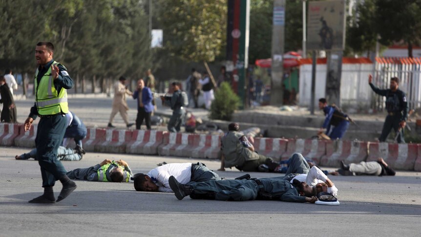 Afghan security personnel and traffic police lie on the ground after a suicide attack