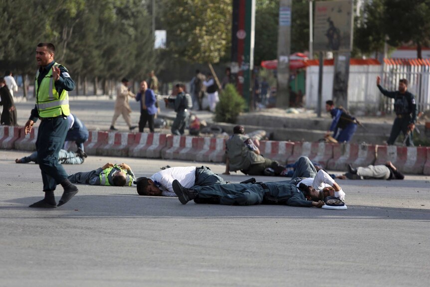 Afghan security personnel and traffic police lie on the ground after a suicide attack