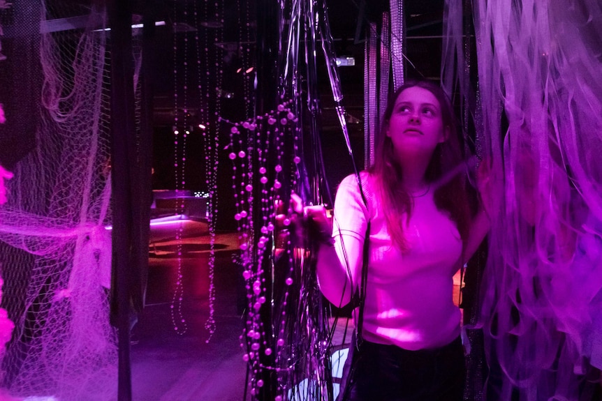 A young woman walks between the different textures of the art exhibit