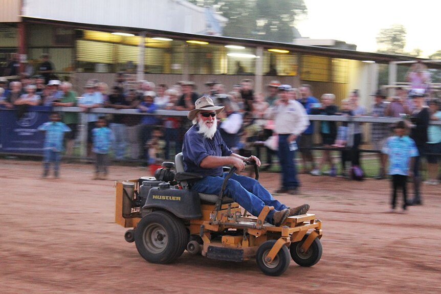 A man rides a mower in a mower race in Boulia.