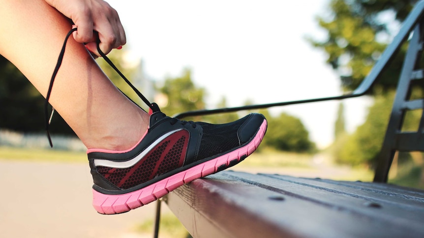 A close-up of a person lacing up their joggers