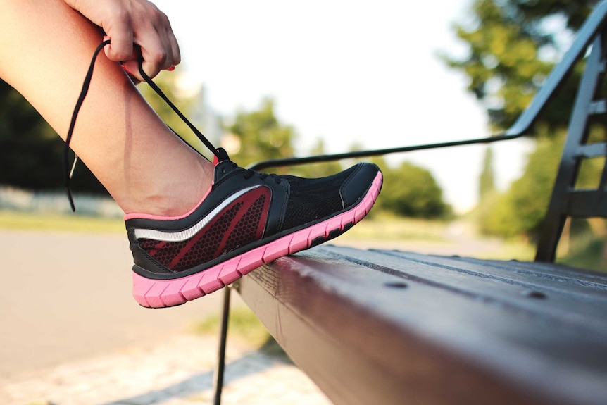 A close-up of a person lacing up their joggers