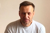 Alexei Navalny sits on a bed in a hospital in Moscow with facial swelling.