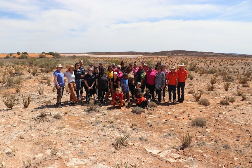 A group of women and children standing in the desert.