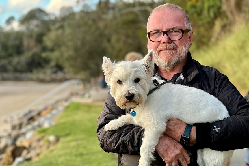 Man looking at camera with white fluffy dog