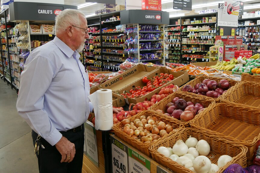 An older man in a supermarket looking at the produce.