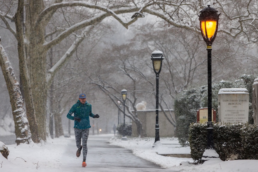 A man jogs down a snowy street in a blizzard