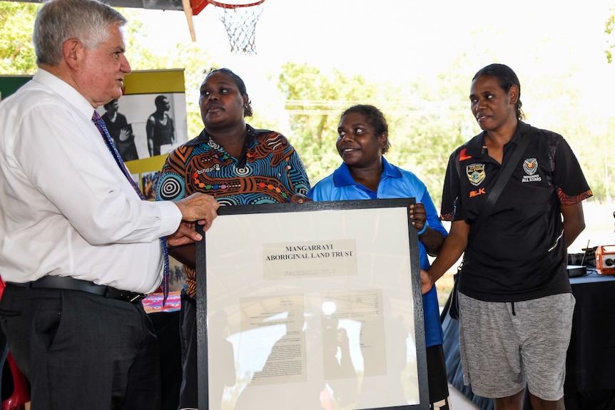 ndigenous Affairs Minister Ken Wyatt and three women talking onstage at a land handback ceremony.