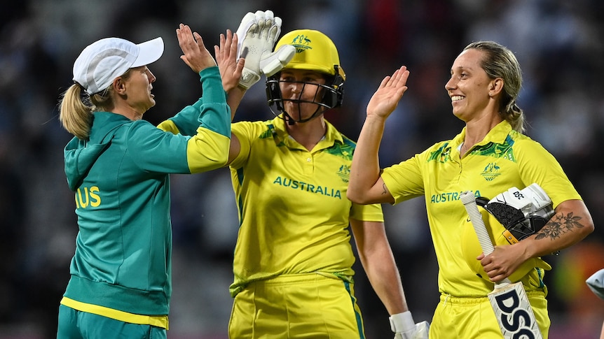 Two Australian batters and the team captain high-five at the end of a T20 match at the Commonwealth Games. 