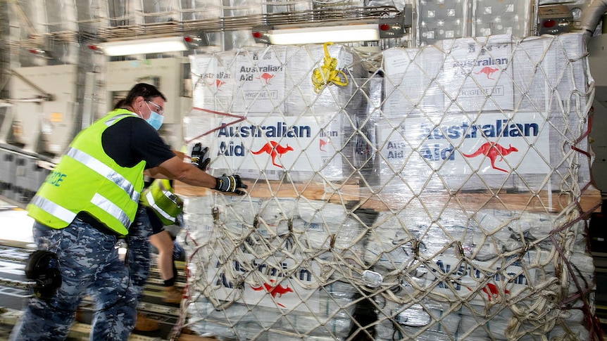 A member of the Australian Air Force loads aid packages onto a plane