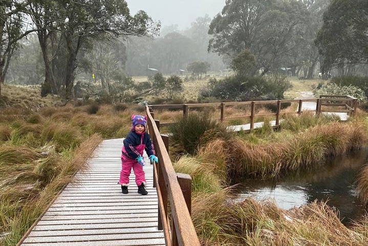 Children in snow jumpers enjoying a light sprinkle of snow on a walkway in the Barrington Tops on the Mid North Coast.
