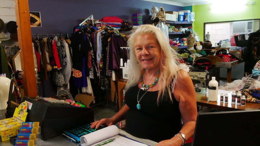 Woman smiling behind a shop counter.