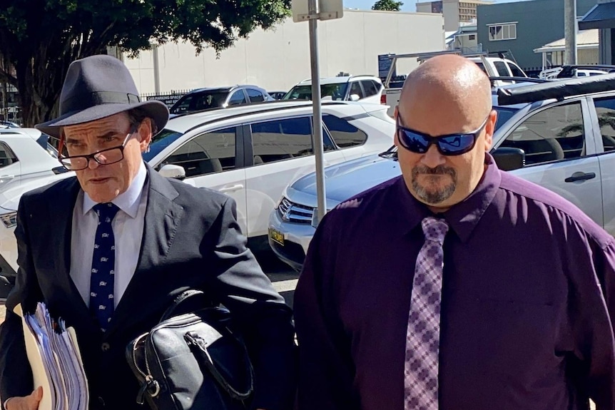 Michael Glenn Lewis wears sunglasses on the right, as he walks in with his lawyer.