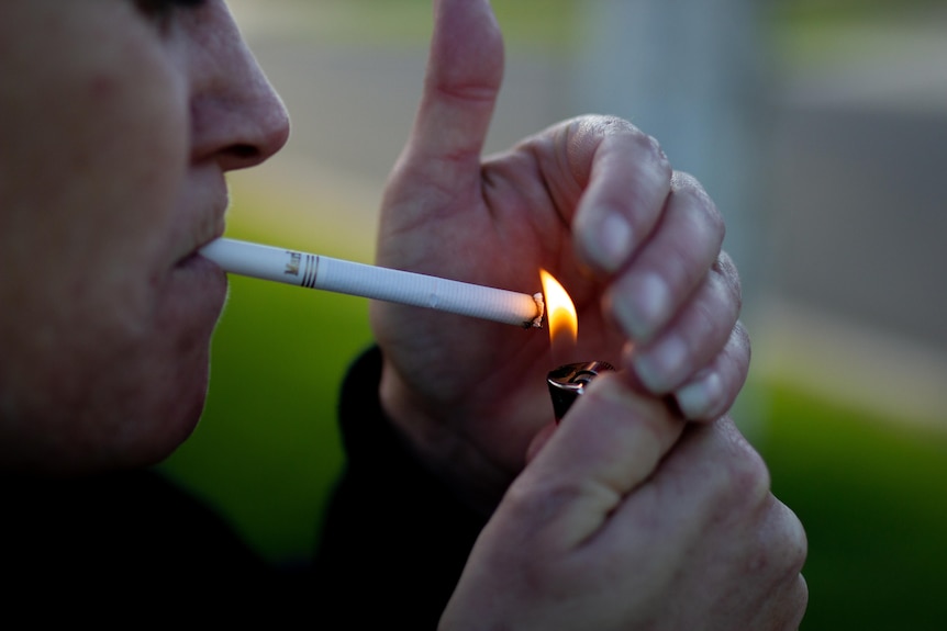 A hand cups a cigarette while it is being lit