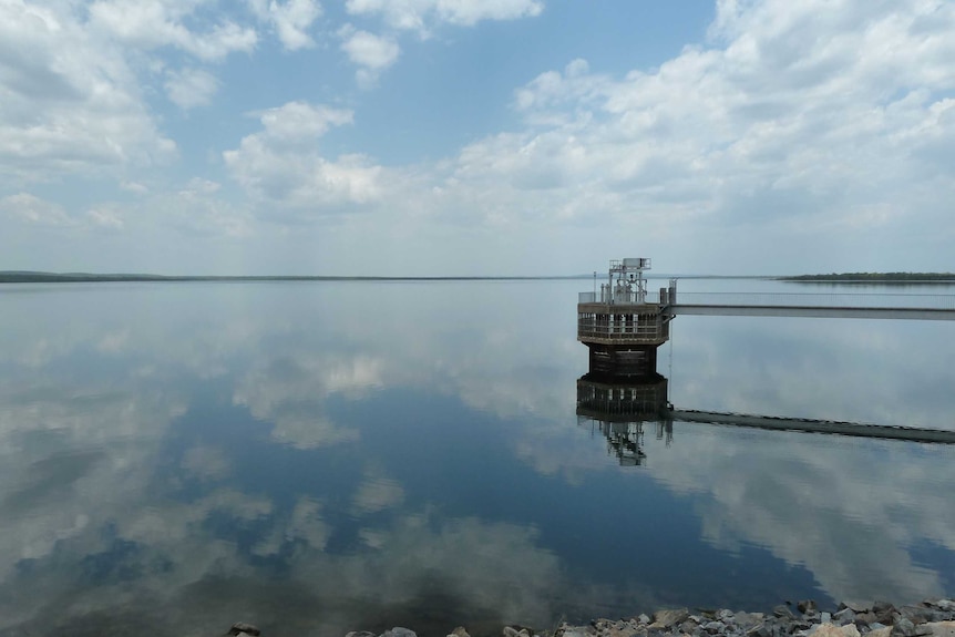 The water on Darwin River Dam is glassy. A gangway juts out into the water.