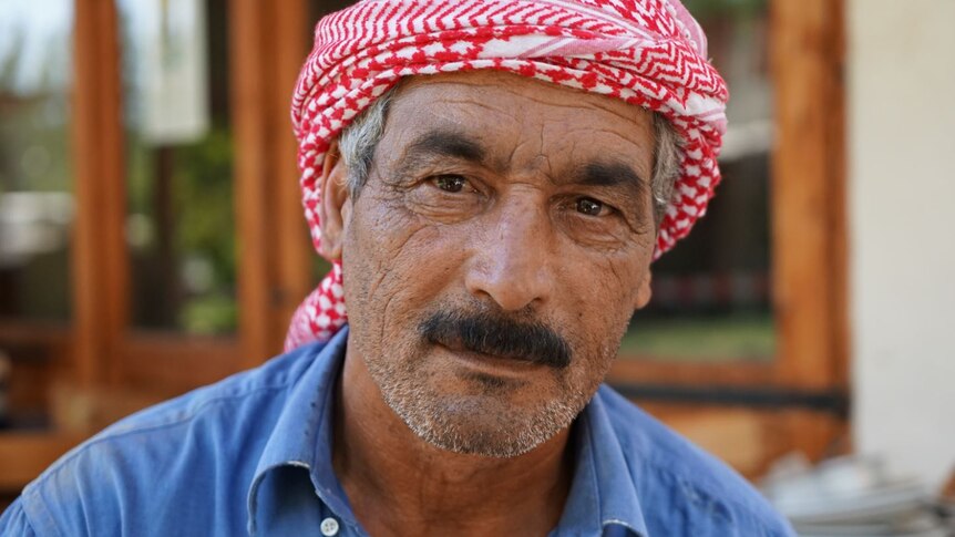A close up photo of a man of a middle-aged Syrian man with a moustache.