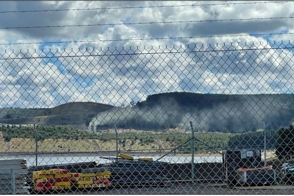 White dust rising from the ground. Wire fence in the foreground.