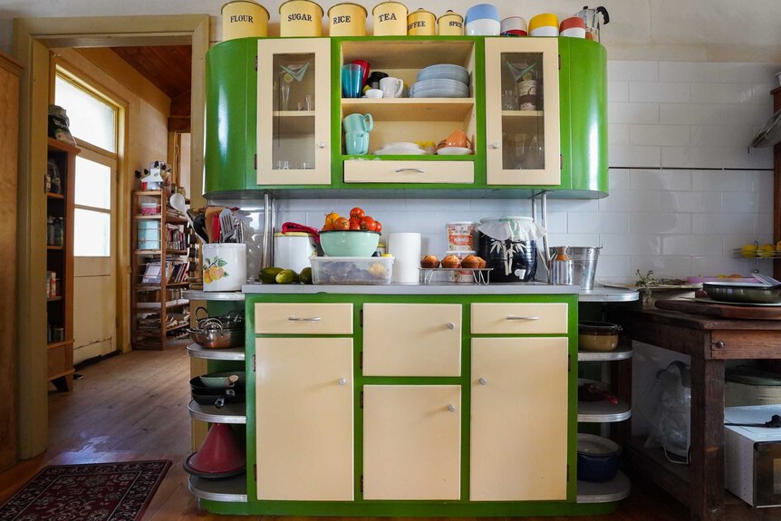 A brightly painted green and beige cabinet from the 60s stands out against a white tiled wall in the Hanels' renovated kitchen.