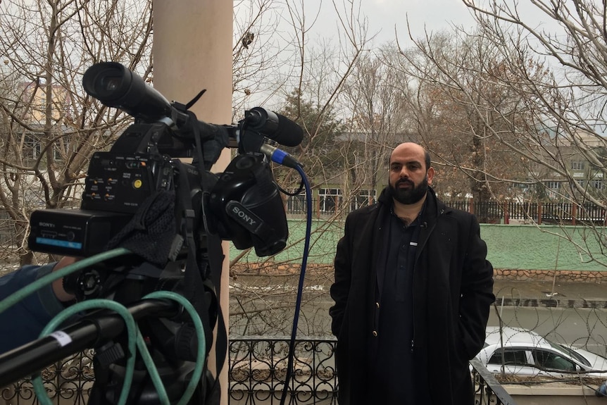 Afghan journalist Bilal Sarwary stand in front of a television camera.