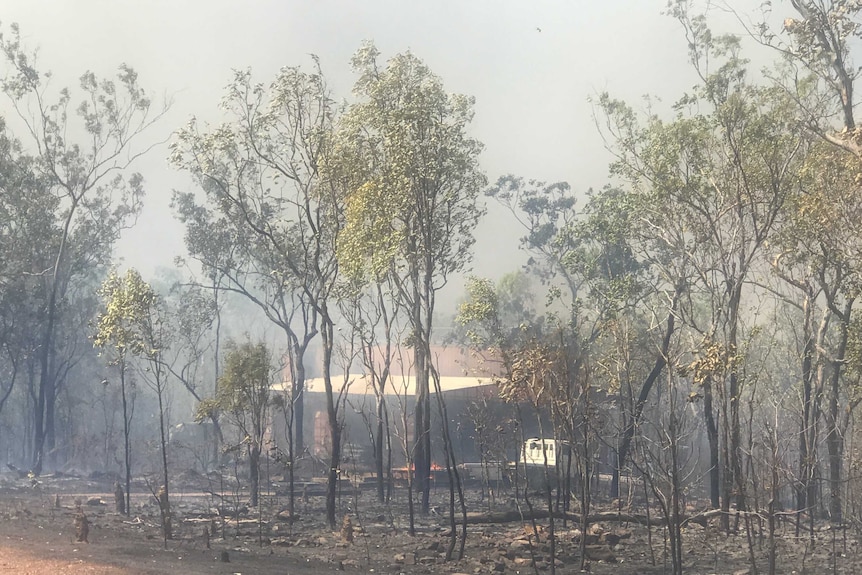 Blackened ground with a fire burning near a truck in the distance