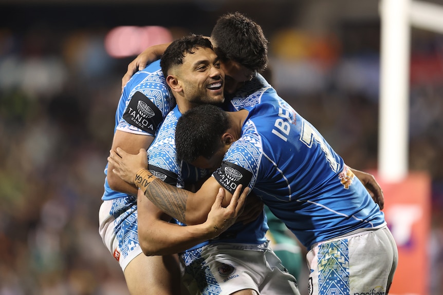 David Nofoaluma is hugged by two Samoa teammates after a try against Cook Islands.