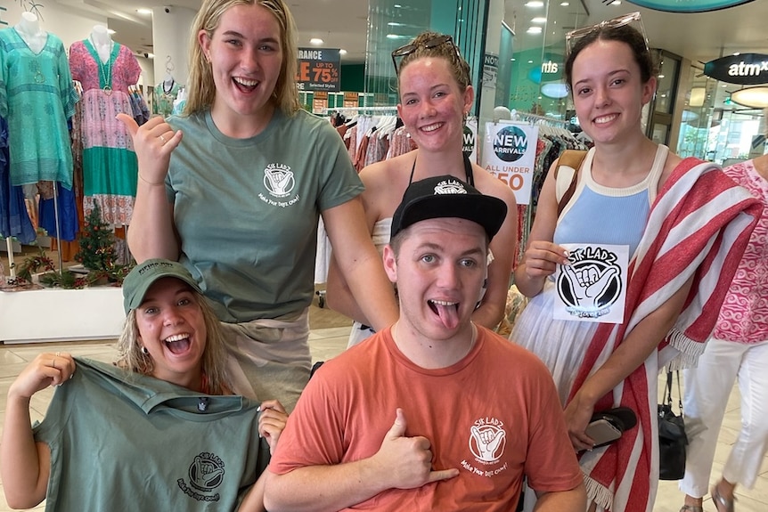 Tristan in wheelchair pokes his tongue out and gives thumbs up surrounded by girls on schoolies