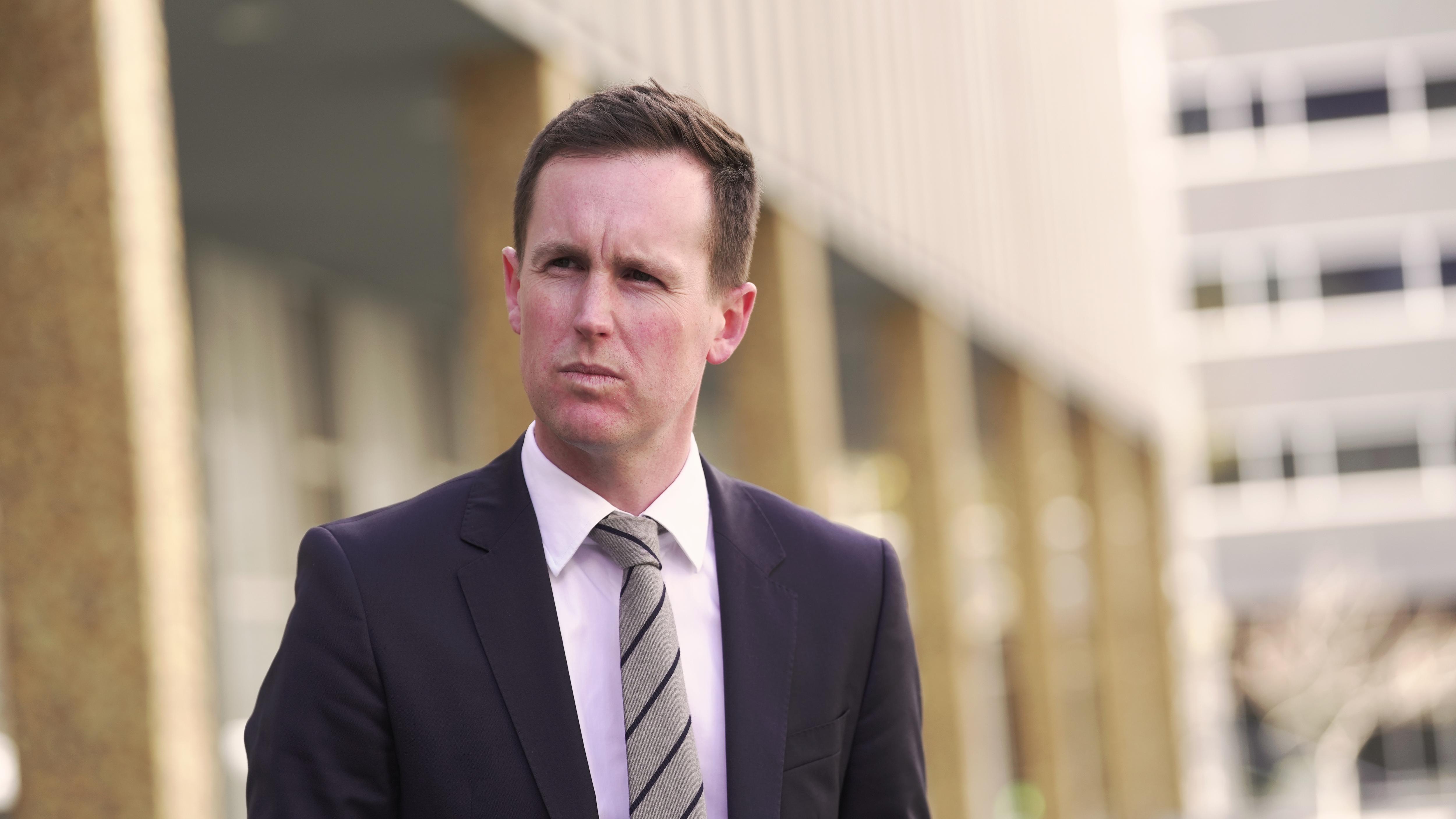 A man stands outside a building speaking to reporters.