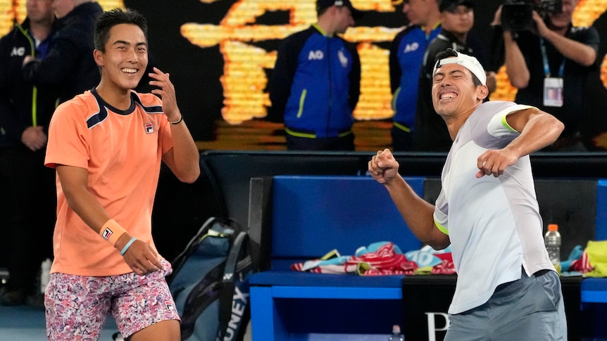 Two Australian tennis players celebrate after winning the Australian Open, with one man laughing and the other punching the air.