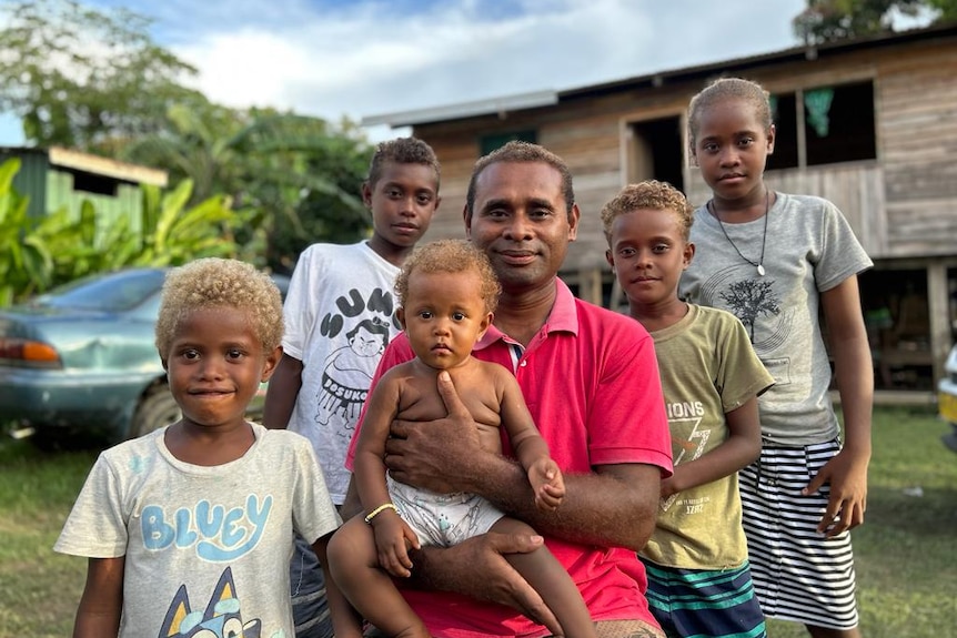 A Solomon Islands man holding a baby.