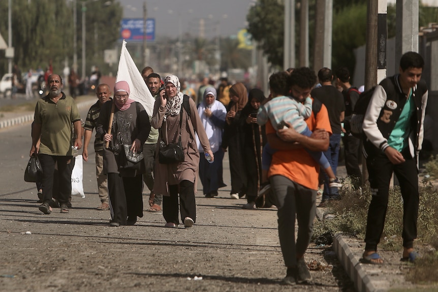 A woman carries a white flag to prevent being shot, as Palestinians flee Gaza City.