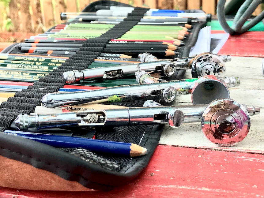 Airbrush tools, pencils all lined up on a table