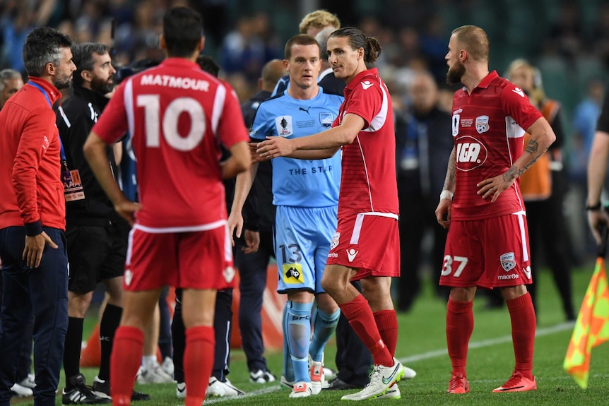 Michael Marrone stans between Adelaide United and Sydney FC players after being sent off in the FFA Cup final.