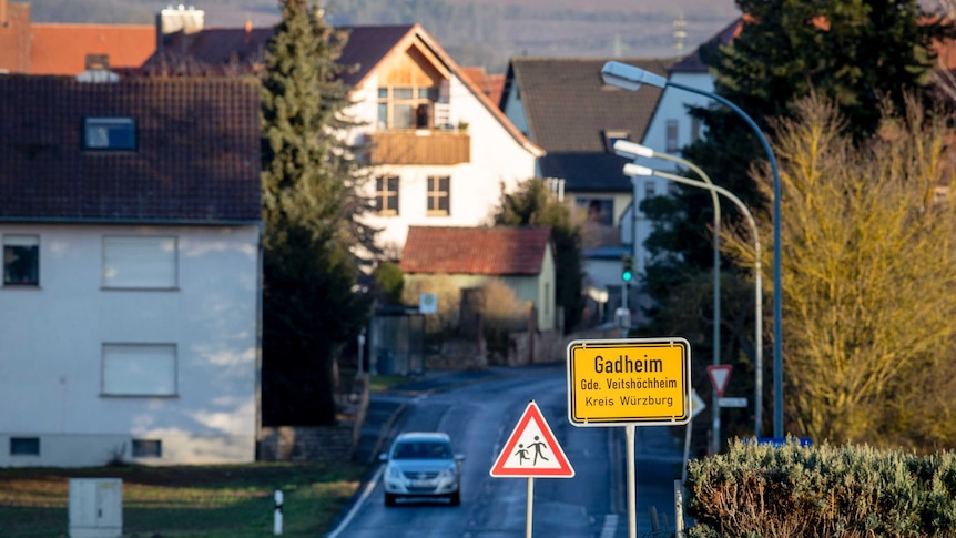 A car drives down an empty road in the village of Gadheim.