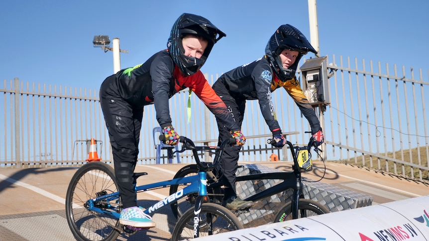 two children in cycling gear and helmets on BMX bikes