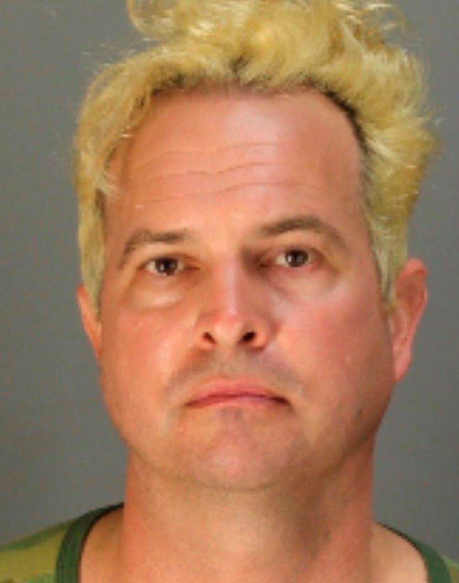 The mugshot of a man with bleached blond hair