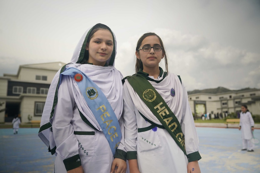 Two girls in prefect uniforms in a playground