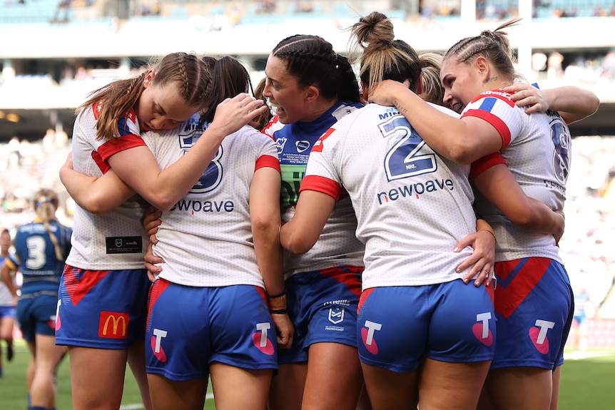 A group of Newcastle Knights NRLW players embrace as they celebrate a try in the grand final.